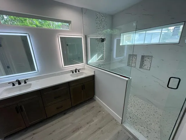 a bathroom with a double vanity sink a mirror and a shower