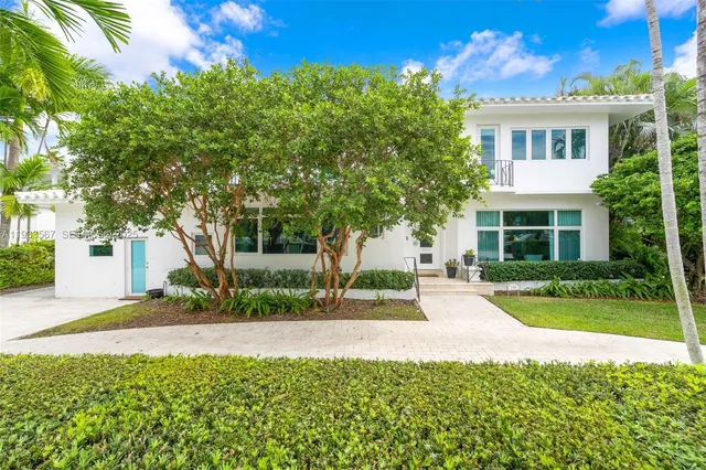 a front view of a house with a yard and potted plants