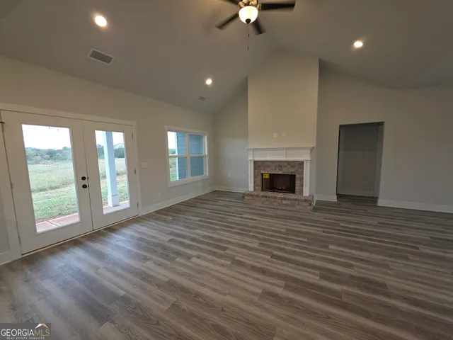 an empty room with windows fireplace and wooden floor