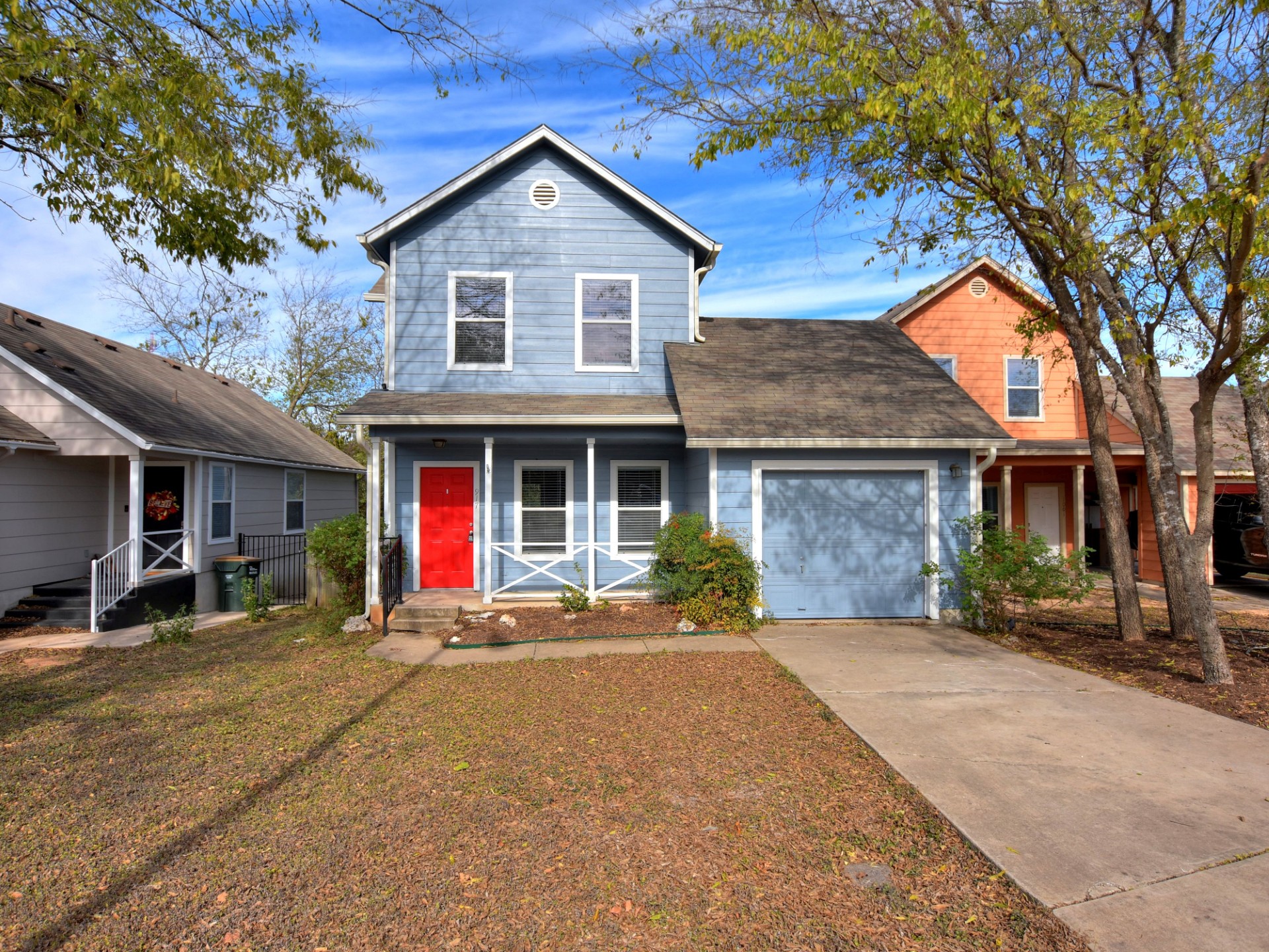 A charming blue residence with a welcoming red entry door awaits, featuring a covered porch.