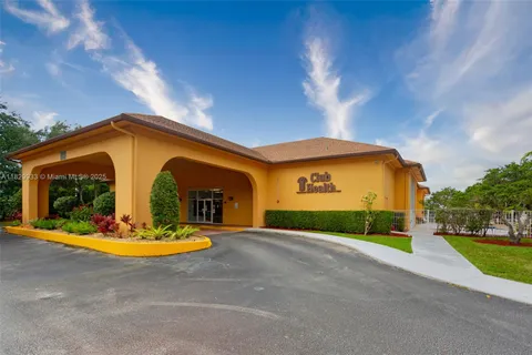 a view of a house with small yard plants and large tree