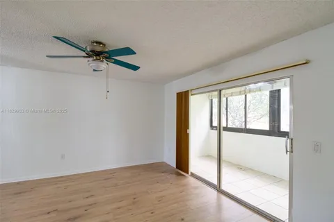 a view of an empty room and window with a ceiling fan