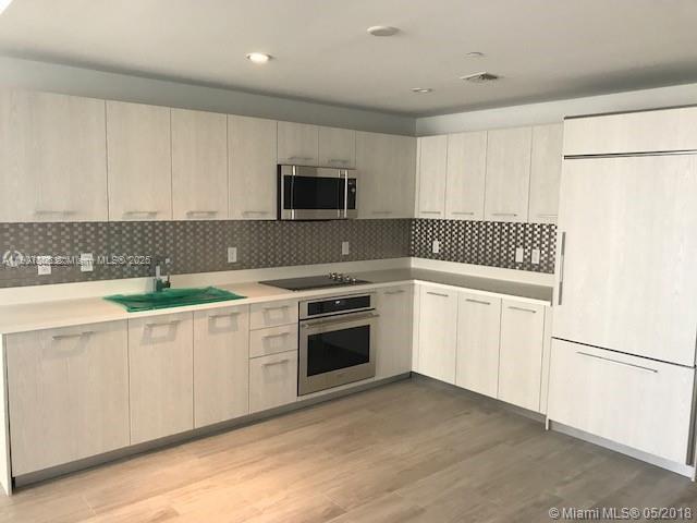 55 Southwest 9th Street, Unit 2510 Miami, FL 33130 - Photo 2 of 27 a kitchen with granite countertop white cabinets and stainless steel appliances