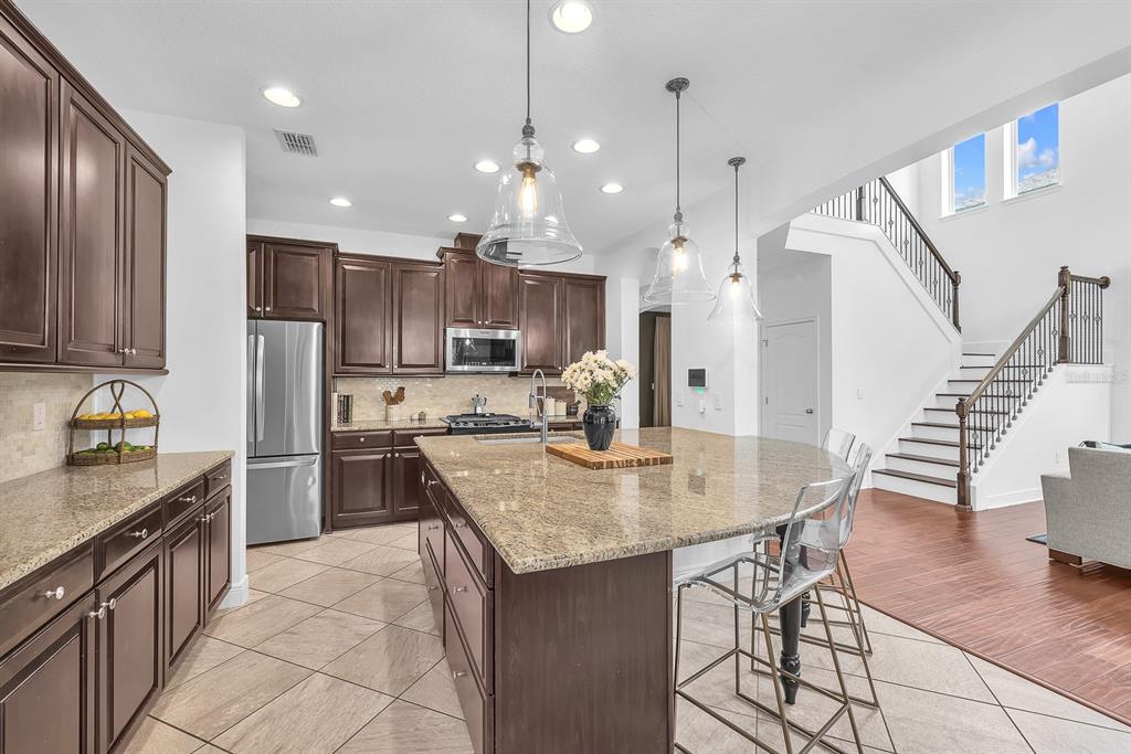 5310 Fishhawk Ridge Drive Lithia, FL 33547 - Photo 15 of 52 a kitchen with granite countertop kitchen island stainless steel appliances a stove a sink a refrigerator a center island a table and chairs