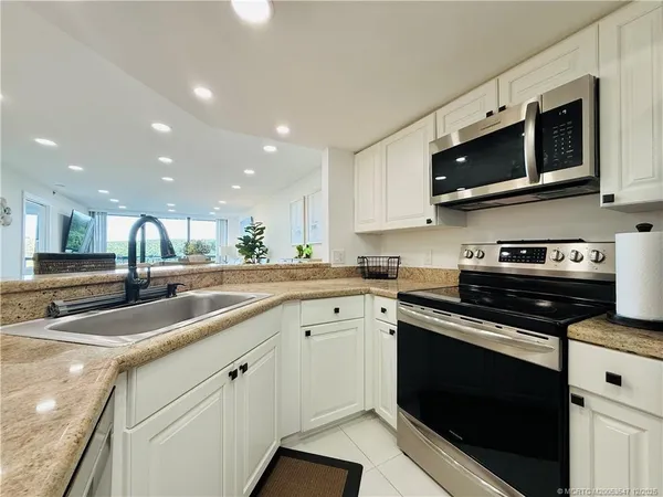 a kitchen with stainless steel appliances a dining table chairs and white cabinets