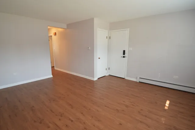 a view of an empty room with wooden floor and closet