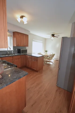 a kitchen with stainless steel appliances granite countertop a refrigerator a sink dishwasher a stove and white countertops with wooden floor