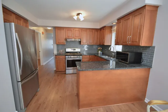 a kitchen with stainless steel appliances granite countertop a refrigerator a stove top oven a sink and dishwasher