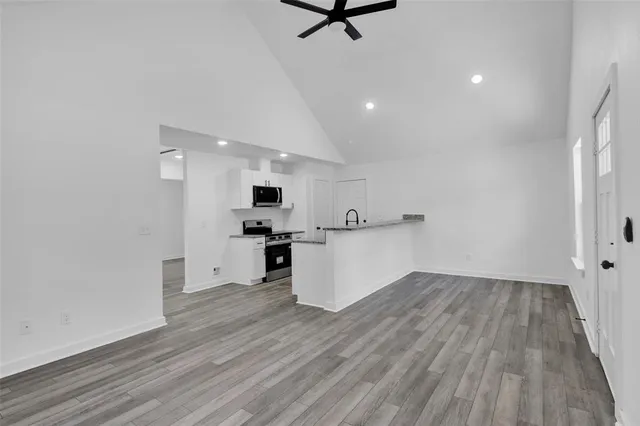 a kitchen with a sink dishwasher and white cabinets with wooden floor