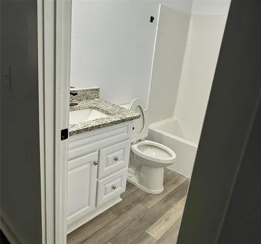 a bathroom with a granite countertop toilet a sink and a mirror