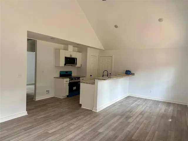 a view of a kitchen with wooden floor and electronic appliances