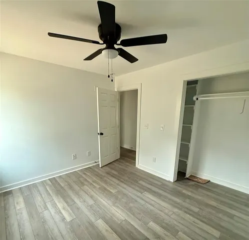 an empty room with wooden floor closet and fan