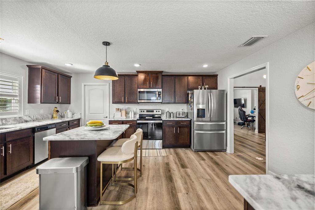 4160 Southwest 100th Street Ocala, FL 34476 - Photo 19 of 42 a kitchen with stainless steel appliances kitchen island granite countertop a sink refrigerator and cabinets