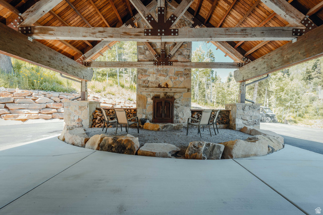 1667 West Tollgate Cyn Road Coalville, UT 84017 - Photo 5 of 61 Expansive outdoor covered patio featuring a stone fireplace, exposed timber beams, Tongue and Groove ceiling, concrete flooring, and natural boulder accents