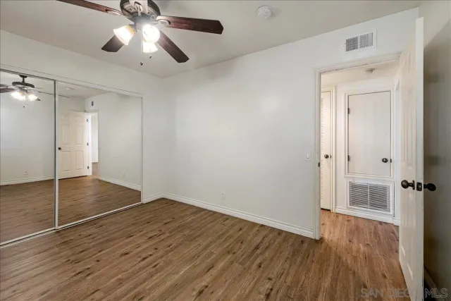 an empty room with wooden floor and a ceiling fan