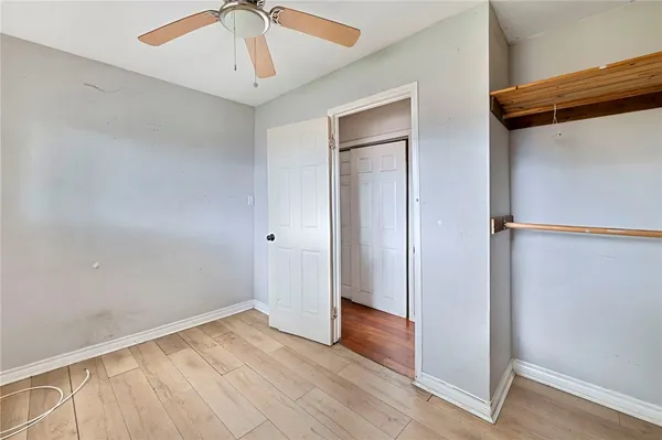 an empty room with wooden floor closet and windows