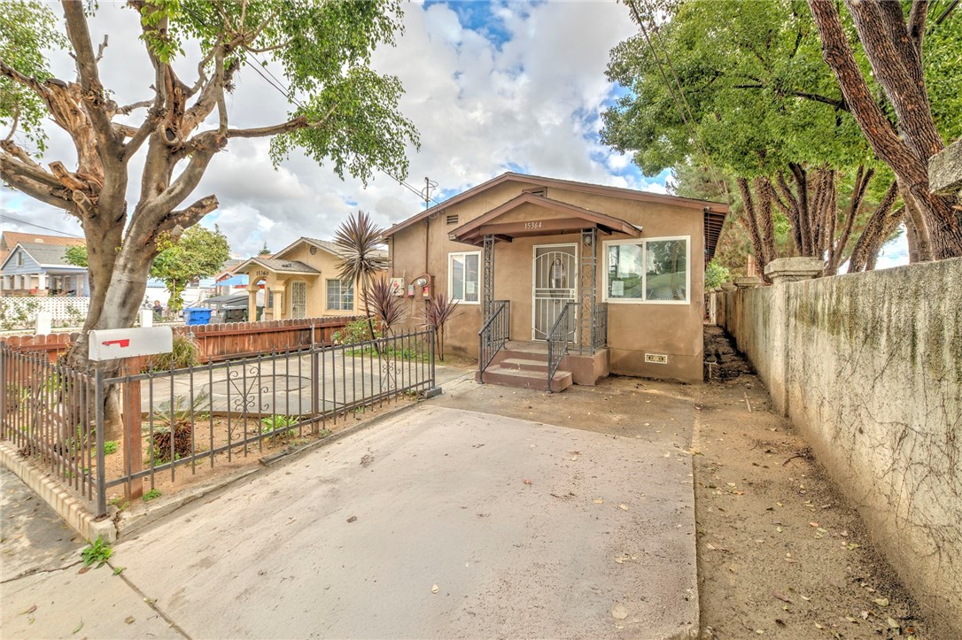 15364 Naranja Avenue Paramount, CA 90723 - Photo 2 of 28 a view of a white house with a large tree and wooden fence