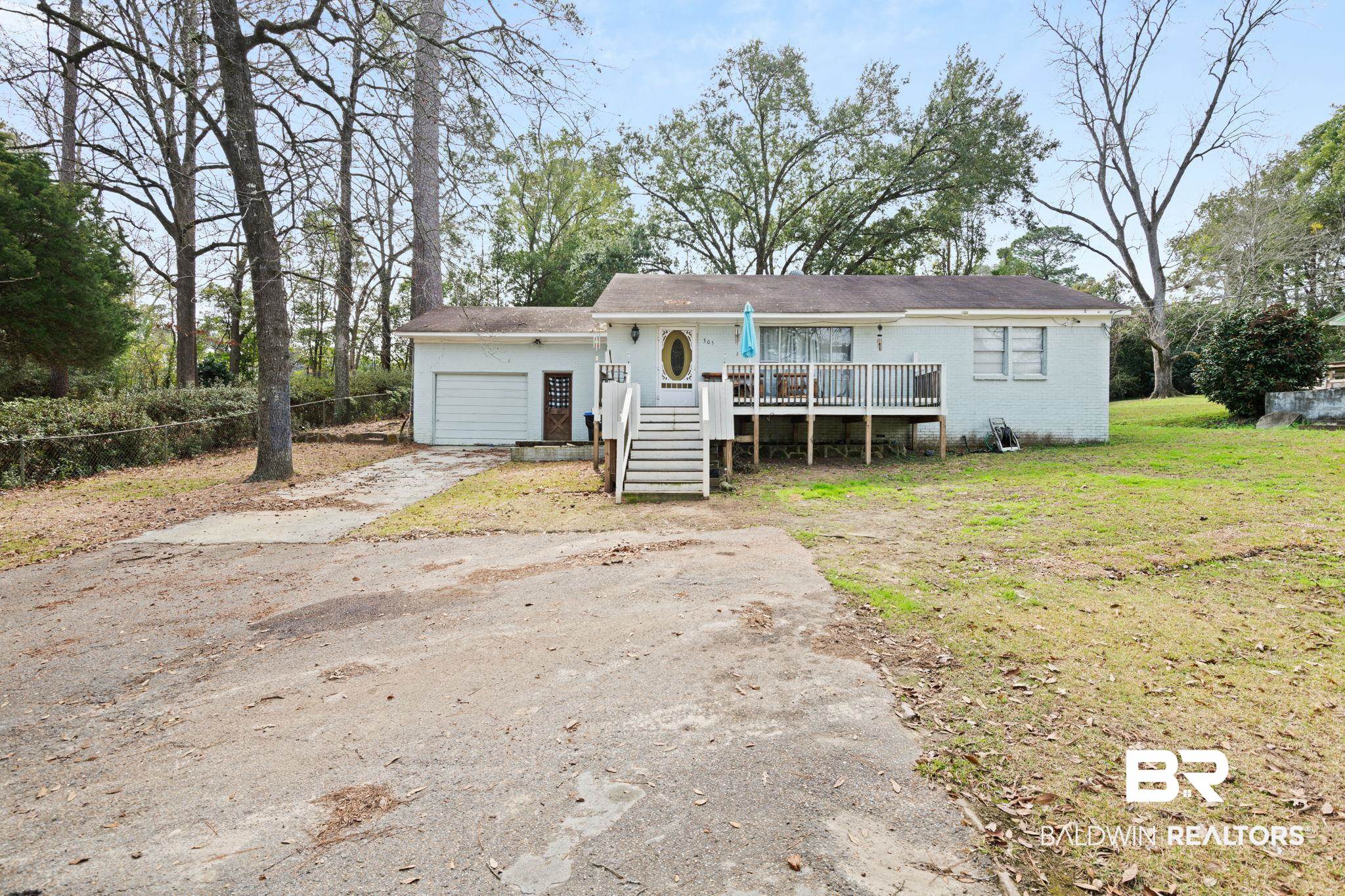 305 Alpine Street Mobile, AL 36611 - Photo 1 of 21 View of front facade with a garage, a deck, and a front lawn