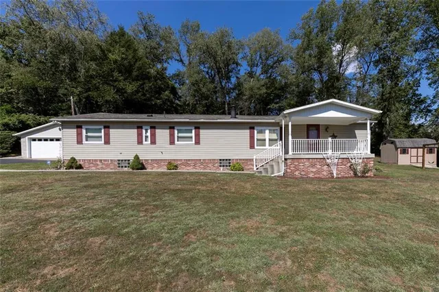 a front view of a house with a yard and trees