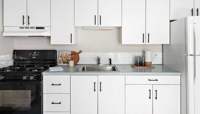 a kitchen with granite countertop a sink a stove and cabinets