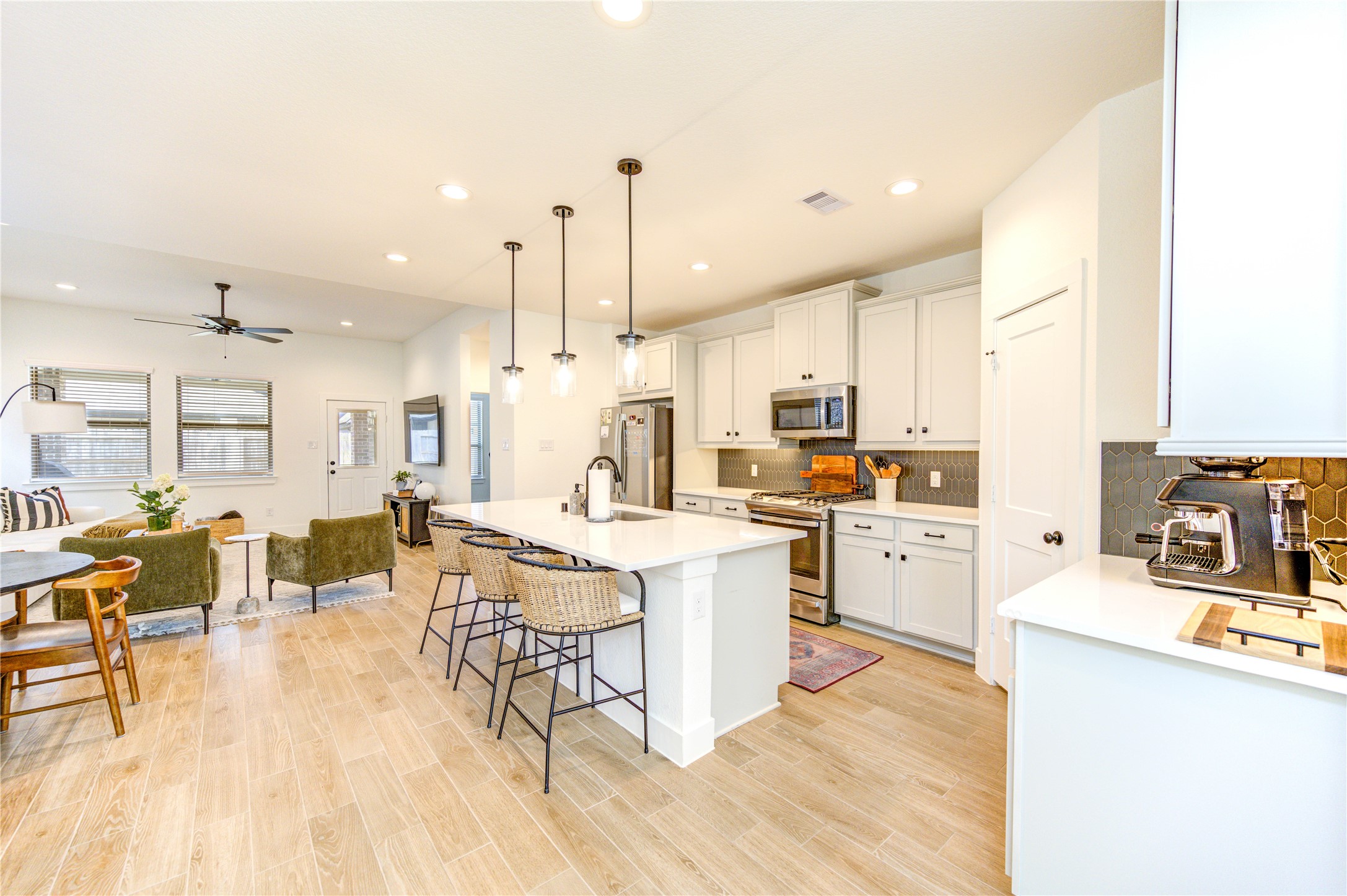 17758 Tree Of Heaven Conroe, TX 77385 - Photo 13 of 44 a kitchen with stainless steel appliances kitchen island granite countertop a stove a sink a refrigerator and white cabinets with wooden floor