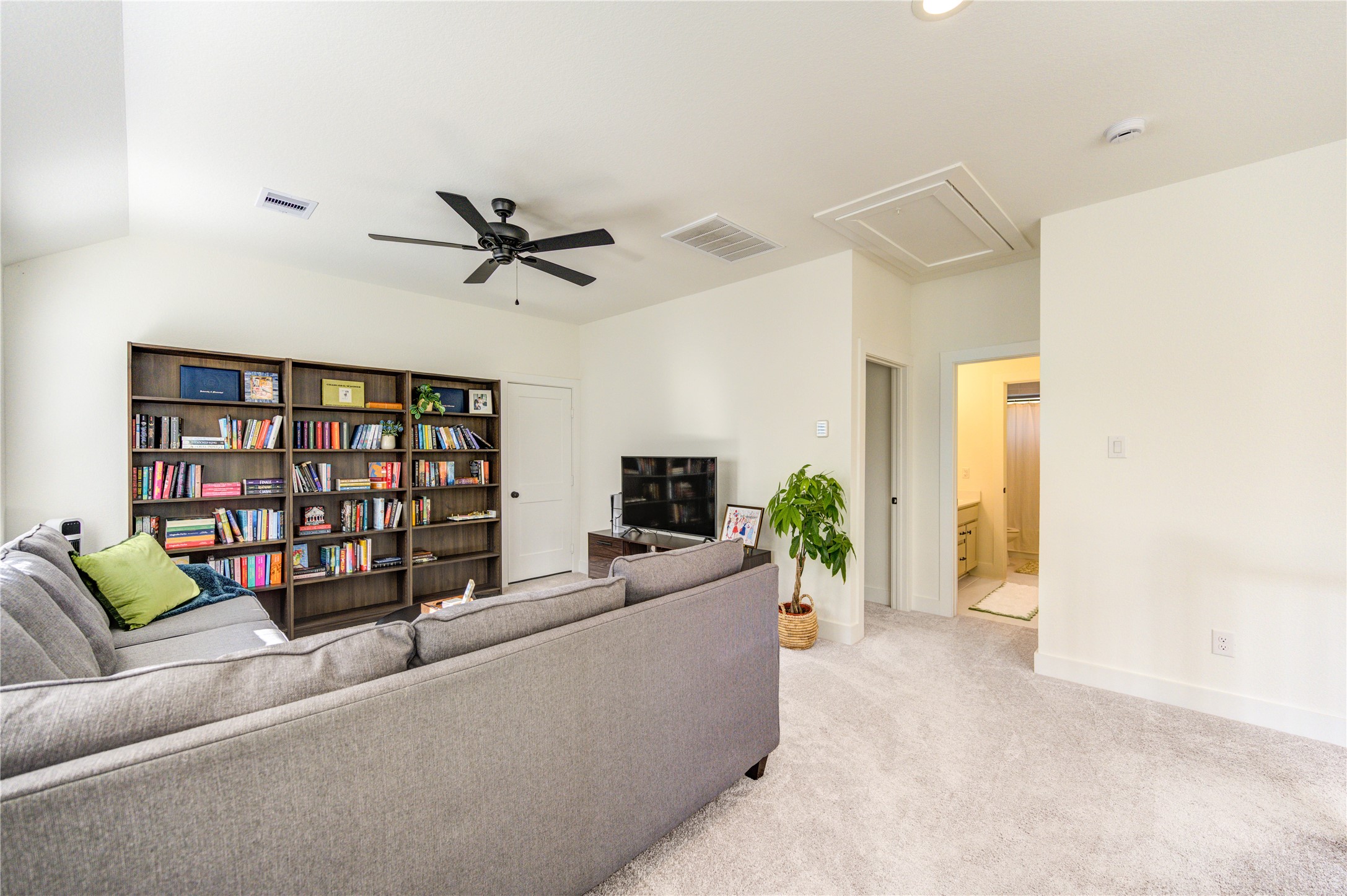17758 Tree Of Heaven Conroe, TX 77385 - Photo 28 of 44 a living room with furniture a ceiling fan a flat screen tv and a book shelf