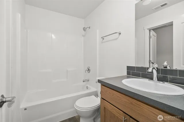 a bathroom with a granite countertop sink a toilet and shower