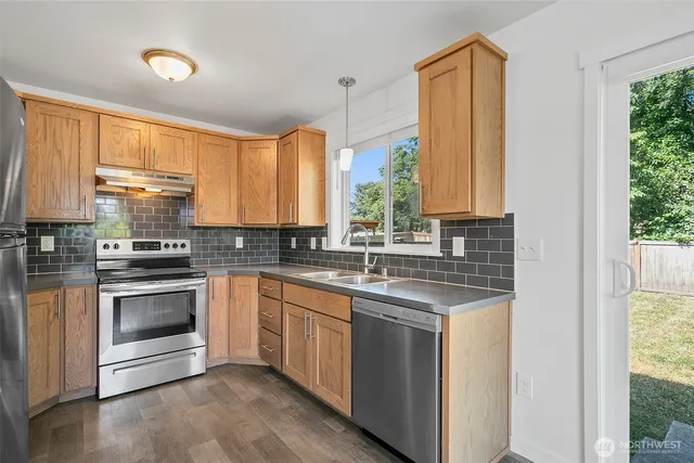 a kitchen with stainless steel appliances granite countertop a stove a sink and a refrigerator