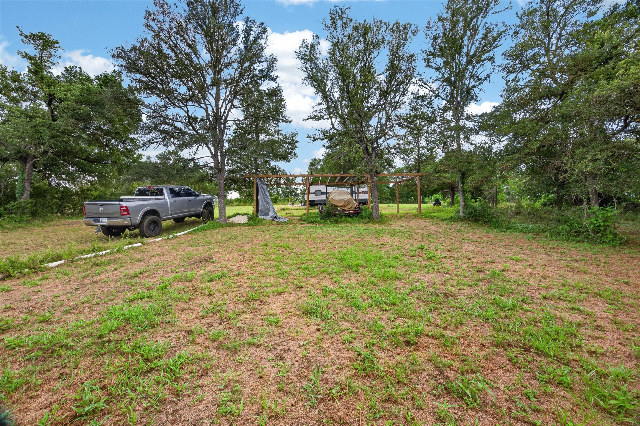 266 Beaver Road Elgin, TX 78621 - Photo 19 of 40 A spacious lot featuring mature trees and a simple outdoor structure, offering ample space and natural privacy.