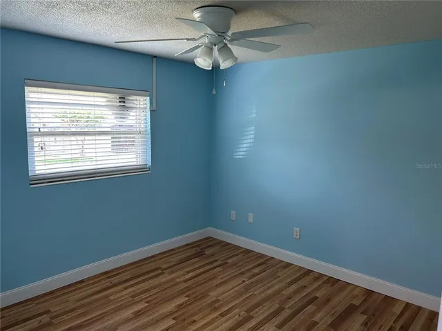 an empty room with a window and a fan