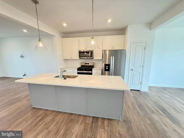 a kitchen with stainless steel appliances a white stove top oven a sink dishwasher and a refrigerator with wooden floor