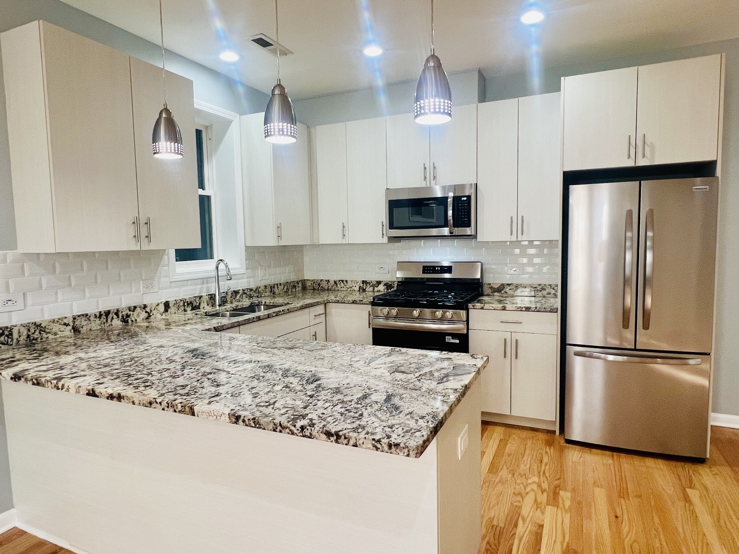 1750 West Cermak Road, Unit B Chicago, IL 60608 - Photo 7 of 18 a kitchen with kitchen island granite countertop a refrigerator oven a sink and white cabinets