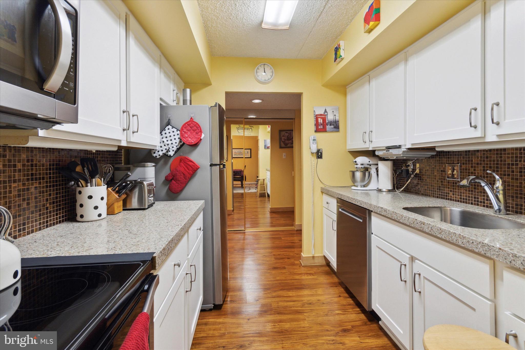 800 Avondale Road, Unit 5L Wallingford, PA 19086 - Photo 8 of 25 a kitchen with a sink dishwasher and a stove with wooden floor