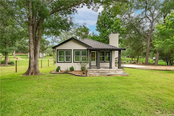 a front view of a house with a yard and trees