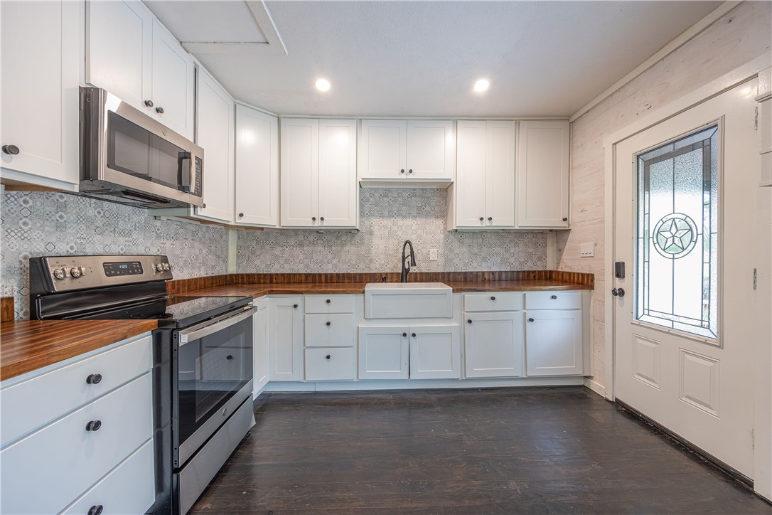 2283 Tigerpoint Road Brenham, TX 77833 - Photo 12 of 27 a kitchen with granite countertop white cabinets stainless steel appliances and sink