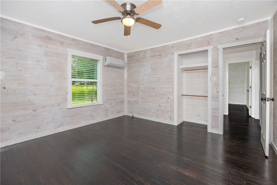 2283 Tigerpoint Road Brenham, TX 77833 - Photo 16 of 27 an empty room with wooden floor chandelier fan and windows