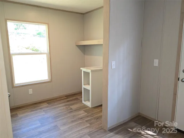 an empty room with wooden floor cabinet and windows