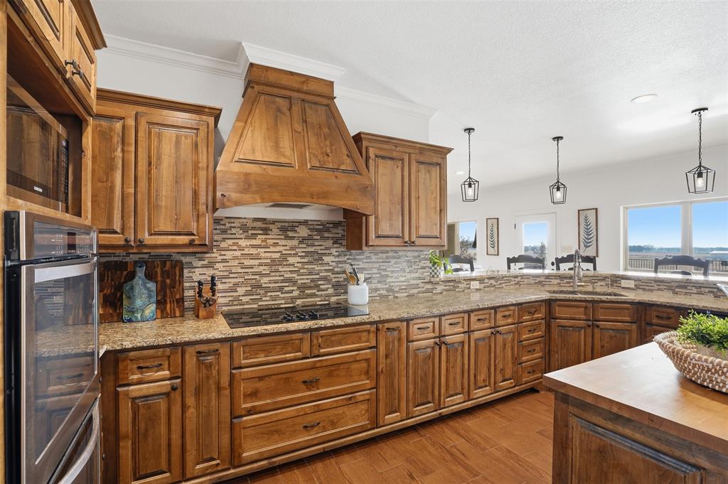 2701 County Road 1110 Rio Vista, TX 76093 - Photo 18 of 39 a kitchen with kitchen island granite countertop wooden cabinets and white appliances