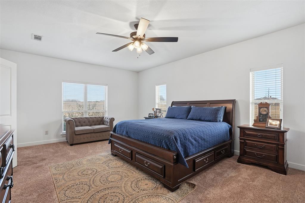 2701 County Road 1110 Rio Vista, TX 76093 - Photo 21 of 39 a spacious bedroom with a bed and a chandelier