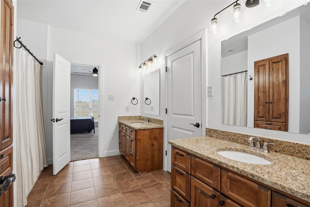 2701 County Road 1110 Rio Vista, TX 76093 - Photo 30 of 39 a spacious bathroom with a granite countertop double vanity sink a mirror and a shower