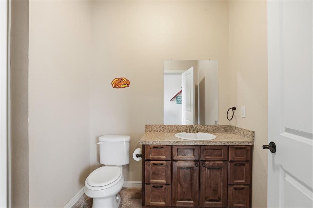 2701 County Road 1110 Rio Vista, TX 76093 - Photo 33 of 39 a bathroom with a granite countertop toilet a sink and a mirror