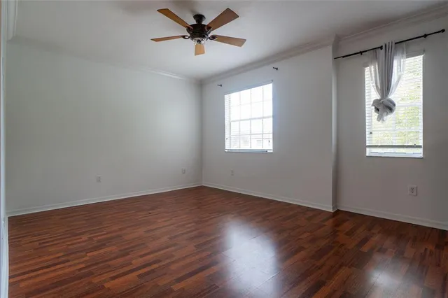 a view of empty room with wooden floor and fan