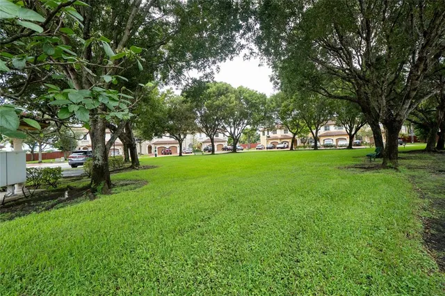 a view of grassy field with benches and trees all around