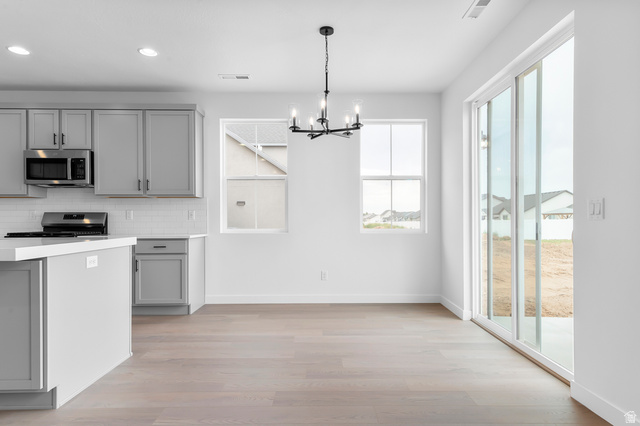 1869 South 2425 West Ogden, UT 84401 - Photo 11 of 22 Kitchen featuring gray cabinetry, backsplash, hanging lights, light wood finished floors, and stainless steel appliances