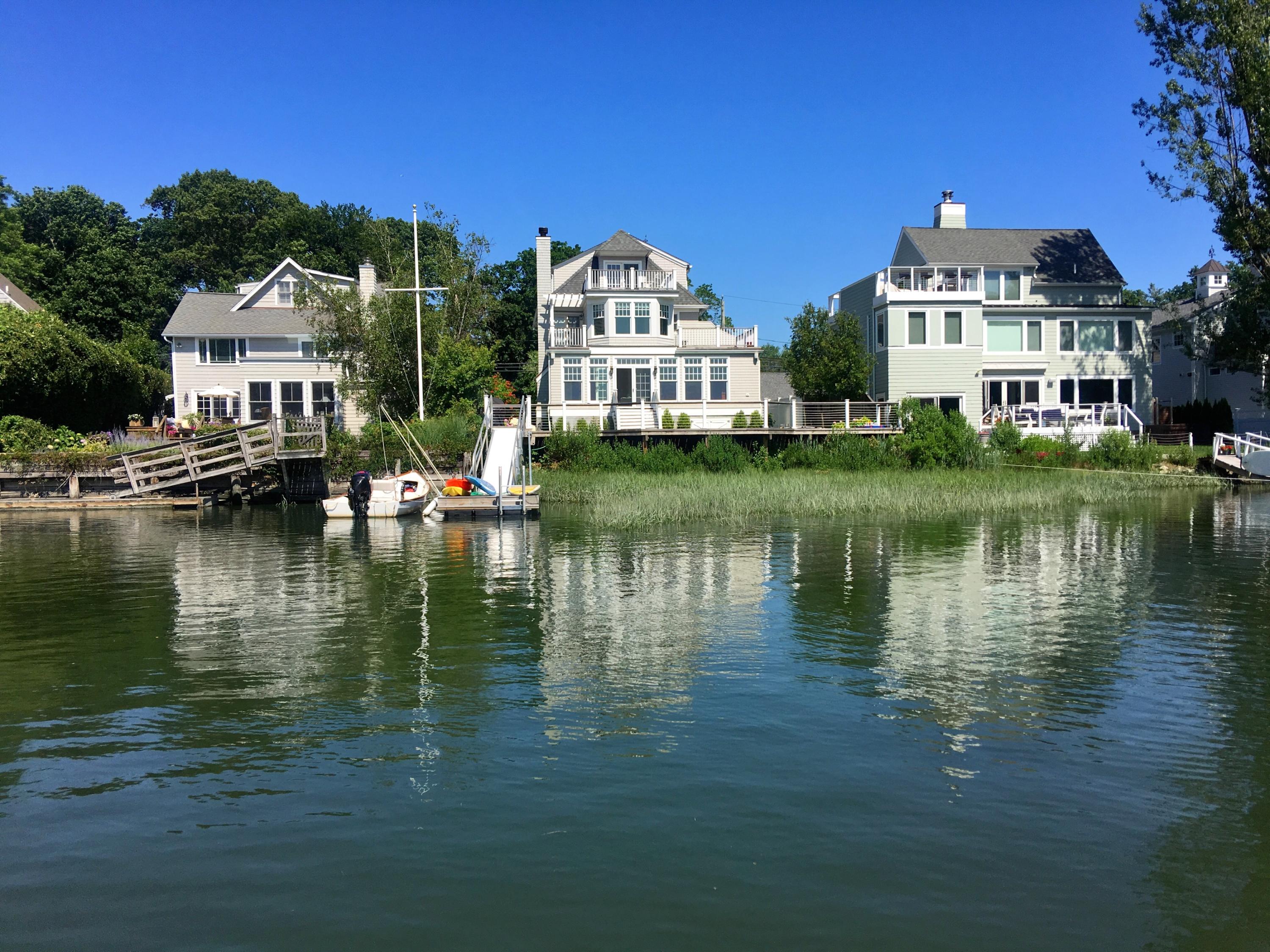a view of a large white building next to a lake with large trees