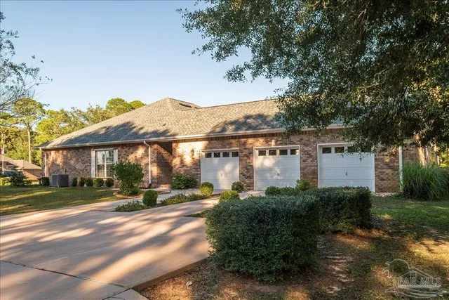 a view of a white house next to a yard with big trees