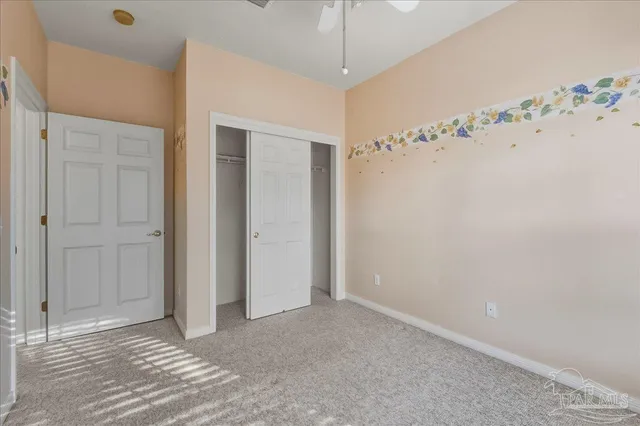 en empty room with window and a chandelier fan