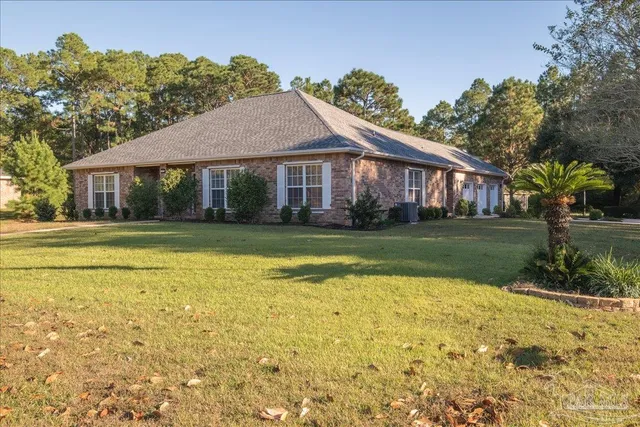 a view of a house with a big yard and potted plants and large tree