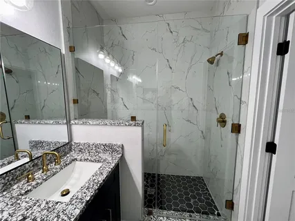 a bathroom with a granite countertop sink a toilet and shower