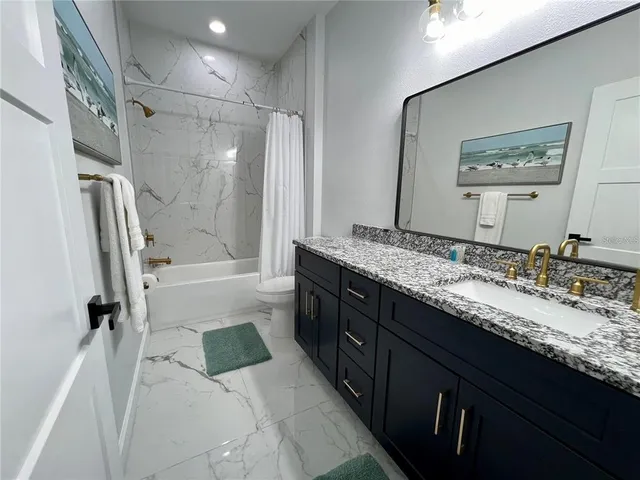 a bathroom with a granite countertop double vanity sink mirror double and shower